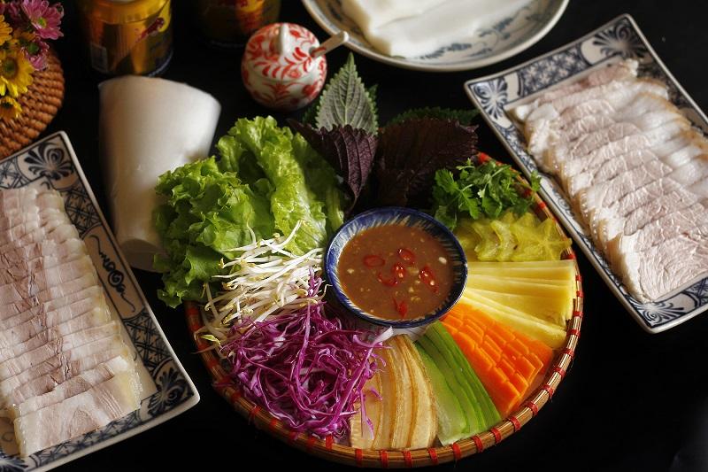 Đĩa bánh tráng cuốn thịt heo hai đầu da đầy màu sắc với nhiều loại rau sống, thể hiện sự đa dạng từ non nước Đà Nẵng